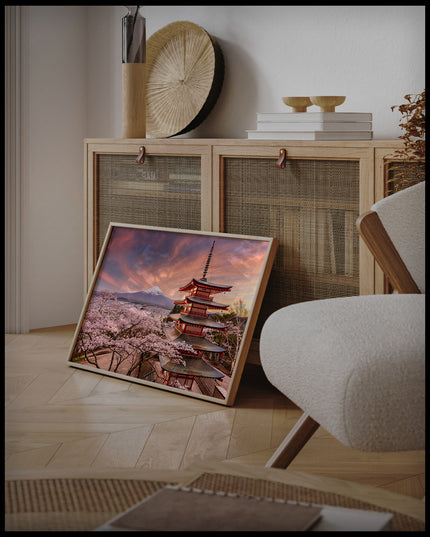 Ein gerahmtes Poster von der Chureito-Pagode vor dem Fuji-Berg bei Sonnenuntergang, umgeben von Kirschblüten, an einer Holzkommode angelehnt und stehend auf dem Holzboden