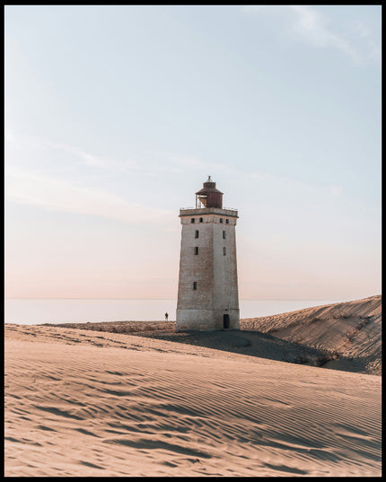 Ein Poster von einem einsamen Leuchtturm in einer sandigen Dünenlandschaft unter einem klaren Himmel.