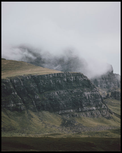 Ein Poster von einem steilen Abhang eines Berges, der von Gras bedeckt und von Nebel umschlungen ist.